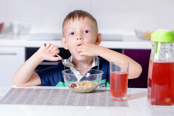 Boy Eating Cherries Off Top of Cereal at Breakfast