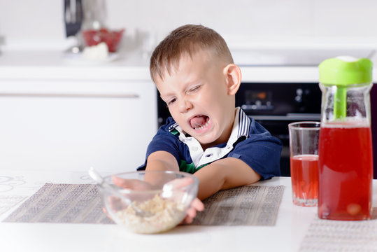 Boy Pushing Away Bowl of Cereal at Breakfast
