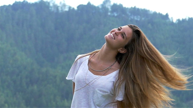 Very slow motion at 120fps of a cute young woman swinging long hair outdoors. Freedom and young people lifestyles series. Blurred background slow panning due to slider motion.