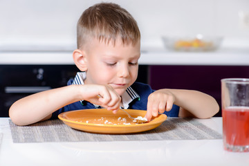 Boy Eating Last Bite of Food at Kitchen Table