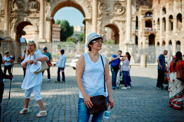 Woman tourist on the background of the Colosseum and arch of Constantine in Rome, Italy