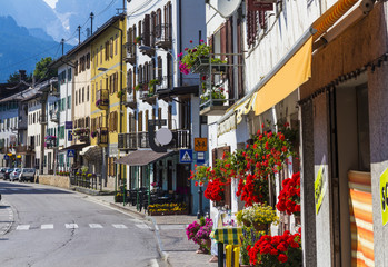 Road in alpine village with red flowers on house balcony