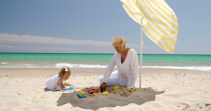 Cute Girl and Grandmother Playing on the Beach