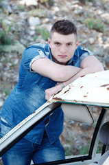 Man in jeans , old damaged car