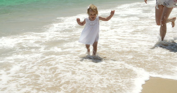 Little girl running along a beach with her mother