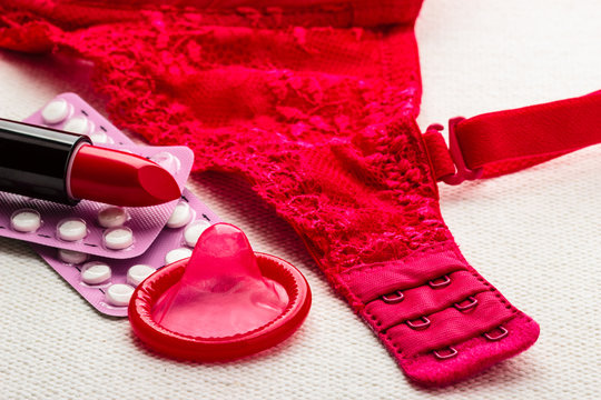 Pills, lipstick and condom with lace lingerie.