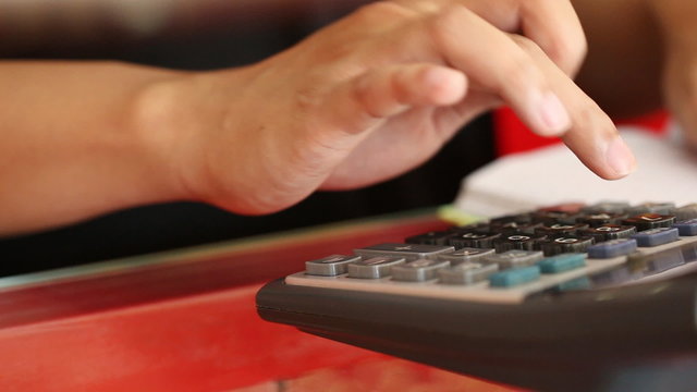 panning shot close-up of hand of businessman using a calculator