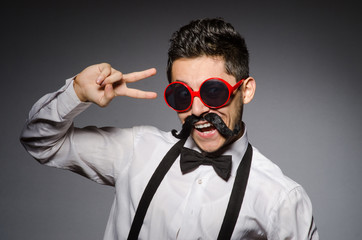 Young man with false moustache isolated on gray