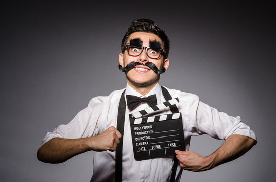 Young man with false moustache holding clapperboard isolated on 