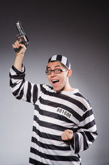 Funny prisoner with firearm isolated on gray