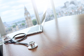 stethoscope and laptop computer on wood table and london bigben