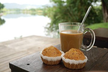 Hot coffee with two banana cupcakes on timber table