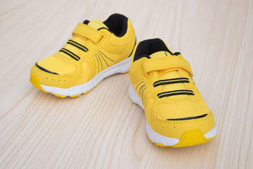 pair of yellow sporty shoes for kid on a wood background