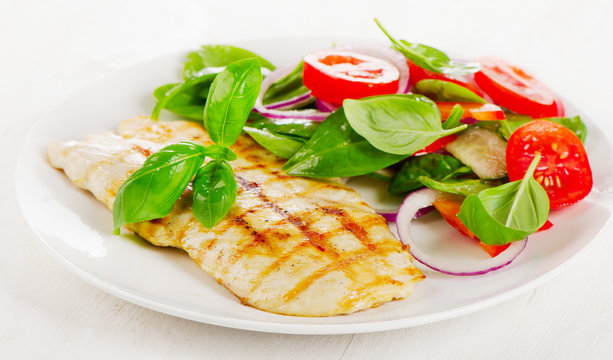 Fresh Salad with grilled chicken on white plate.