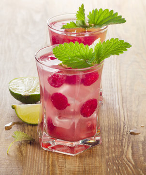 Drink with raspberries, lime and mint  on wooden table.
