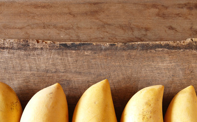 Mangoes in Row on Wooden Background.