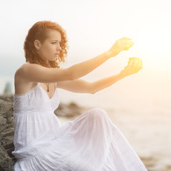 Fototapeta na wymiar Portrait of redhead woman holding zen stones in hand. With sunshine effect.
