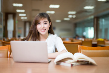 Fototapeta na wymiar Asian beautiful female student study in library with laptop