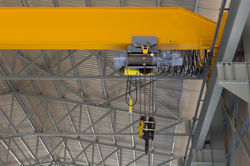 Indoor overhead crane on a yellow steel beam