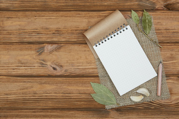 Blank notepad for copy space and herbs on wooden table