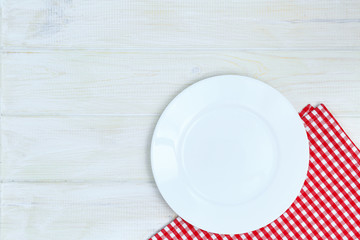 Empty plate and napkin on a white wooden background of a table.