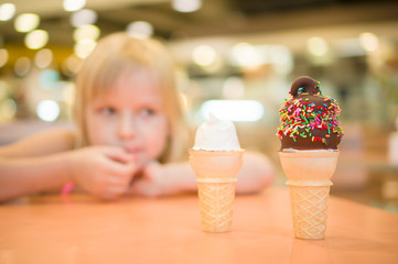 Adorable girl eat chocolate ice cream with sprinkles in mall