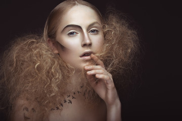 Beautiful girl with a pattern on the body in the form of birds, creative makeup and hairstyle lush. Beauty face. Picture taken in the studio on a gray background.