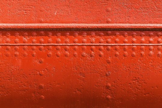 Red metal wall texture with seams and rivets