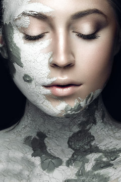 Beautiful girl with mud on his face. Cosmetic mask. Beauty face. Picture taken in the studio on a black background.