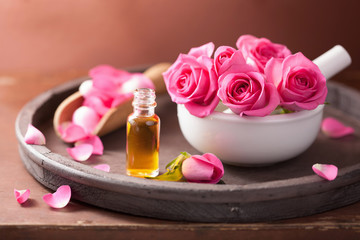 Obraz na płótnie Canvas spa set with rose flowers mortar and essential oil
