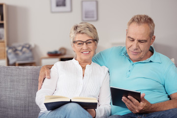 senioren mit buch und tablet-pc zu hause