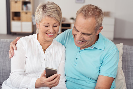 älteres paar schaut gemeinsam auf eine sms am mobiltelefon