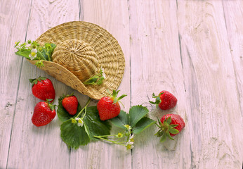 Straw hat with strawberry on wooden background