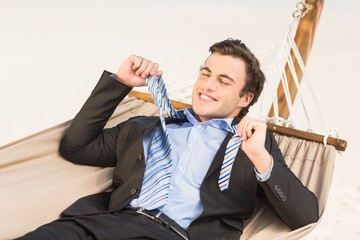 Businessman removing his tie on the hammock