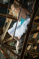 Soft ballerina is sitting on an old rusty ladder.