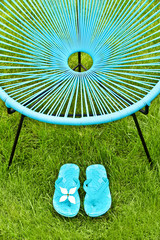 Turquoise blue garden chair and flip flops, green lawn background