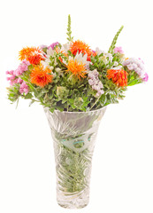 Vivid colored wild flowers in a transparent vase, close up