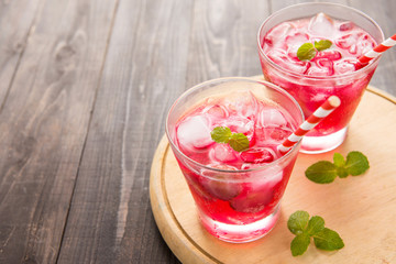 Red Cocktail with mint and ice on wooden table