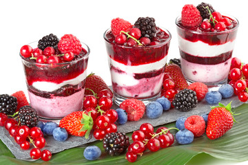 mixed berries dessert on slate and soft fruit on green leaf