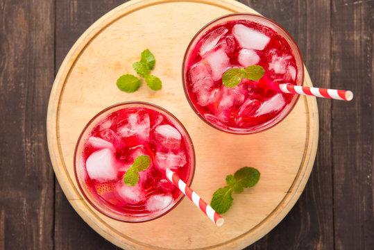 Red Cocktail with mint and ice on wooden table