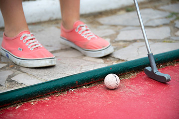 Close up on the feet of a kid playing mini golf