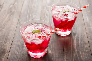 Red Cocktail with mint and ice on wooden table