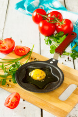 Raw egg in a pan on a white wooden background
