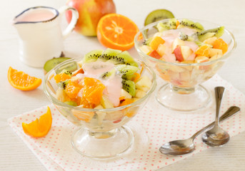 Fruit salad with strawberry in yogurt on a white background wooden