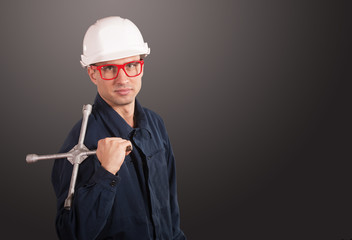 Workman in dark blue coveralls with a wheel wrench