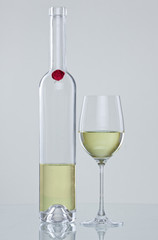 Weißweinflasche und Glas mit Spieglung vor neutralem Hintergrun