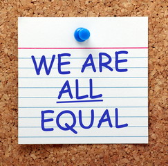 The phrase We Are All Equal in blue text on an index card pinned to a cork notice board as a reminder