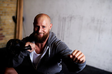 Strong muscular man doing squats with kettlebells