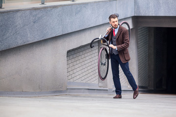 Handsome businessman carrying his bicycle
