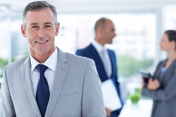 businessman smiling  with two colleague behind him